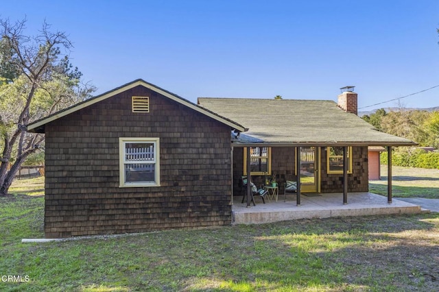 back of property with a patio area, a chimney, and a yard