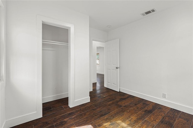 unfurnished bedroom with hardwood / wood-style flooring, a closet, visible vents, and baseboards