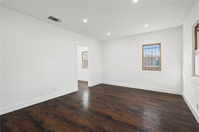 empty room with dark wood-style floors, recessed lighting, visible vents, and baseboards