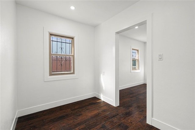 empty room with dark wood-style floors, recessed lighting, and baseboards