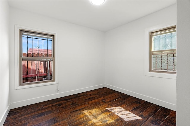 spare room featuring baseboards and dark wood-type flooring