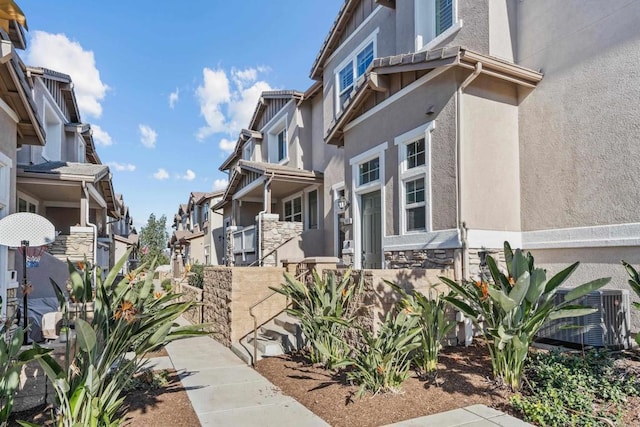 view of property exterior featuring stone siding, a residential view, and stucco siding