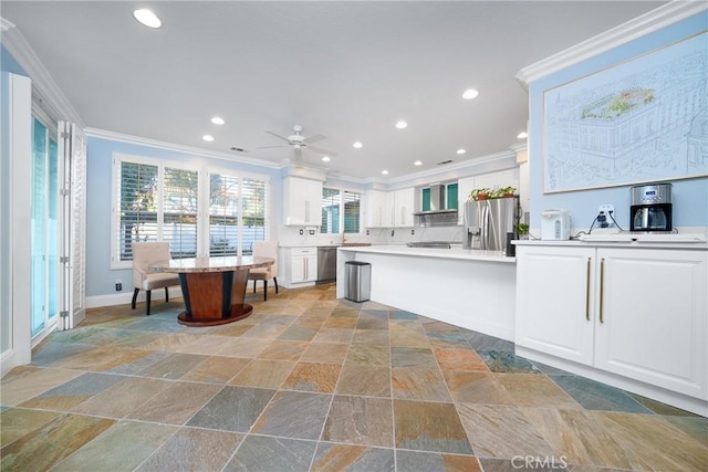 kitchen with stone tile flooring, wall chimney exhaust hood, appliances with stainless steel finishes, and crown molding