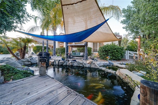 view of dock featuring a garden pond and fence