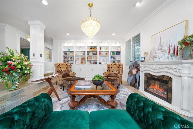 living area with decorative columns, ornamental molding, built in features, and a glass covered fireplace