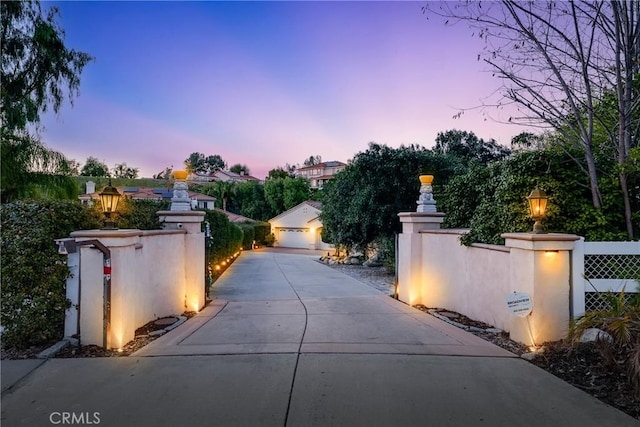 exterior space featuring driveway, a gated entry, and street lights