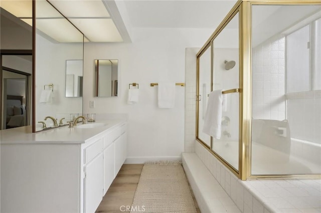 full bath featuring a washtub, a shower with shower door, vanity, wood finished floors, and baseboards