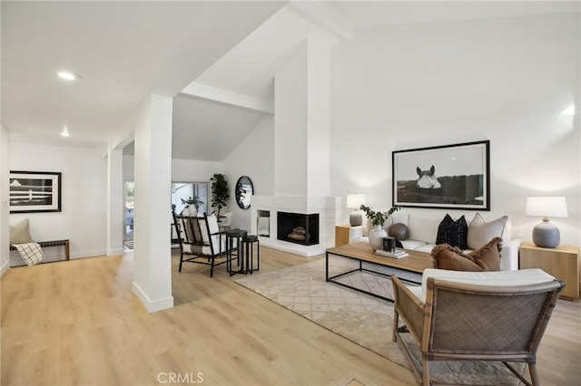 living room with light wood finished floors, baseboards, beamed ceiling, high vaulted ceiling, and a multi sided fireplace