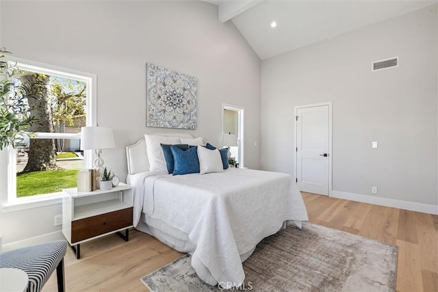 bedroom featuring light wood-type flooring, high vaulted ceiling, visible vents, and beamed ceiling