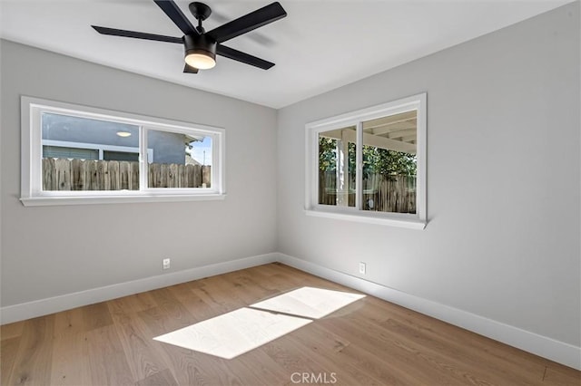 spare room featuring wood finished floors, a ceiling fan, and baseboards