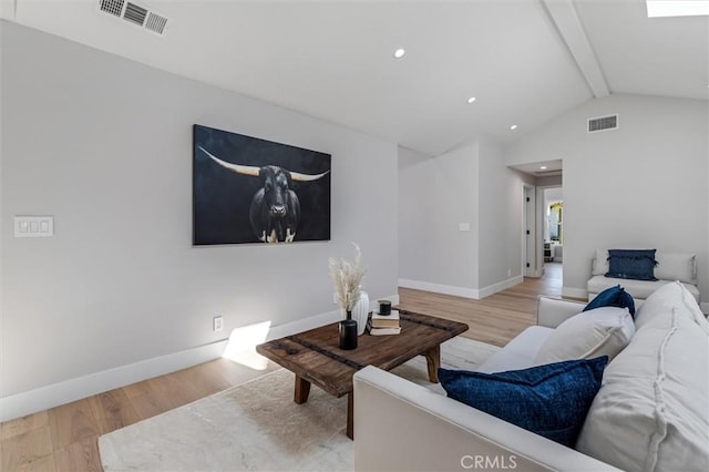 living area with visible vents, lofted ceiling with beams, and wood finished floors