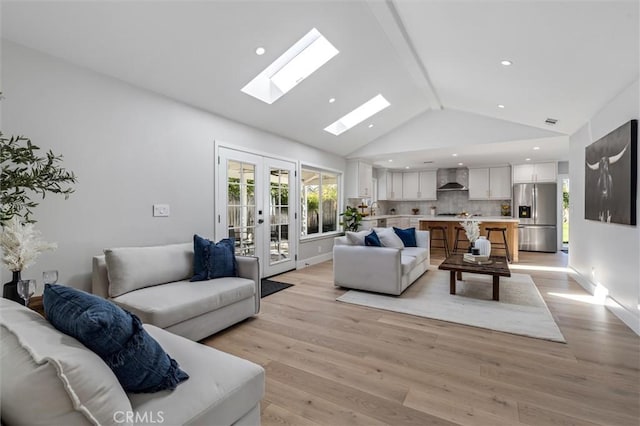 living room featuring a skylight, baseboards, french doors, light wood-style floors, and high vaulted ceiling