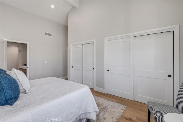 bedroom with visible vents, light wood-type flooring, high vaulted ceiling, multiple closets, and recessed lighting