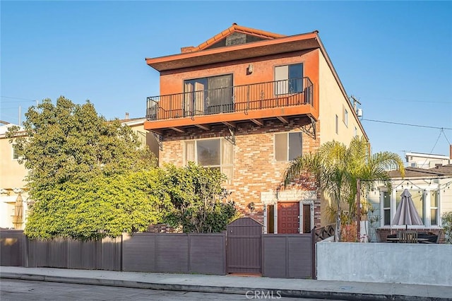 view of front of house featuring a fenced front yard, a gate, a balcony, and stucco siding