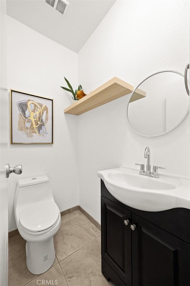 bathroom with toilet, vanity, visible vents, and baseboards