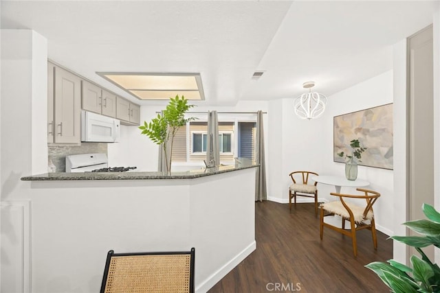 kitchen with white appliances, dark wood-style floors, visible vents, baseboards, and dark stone counters