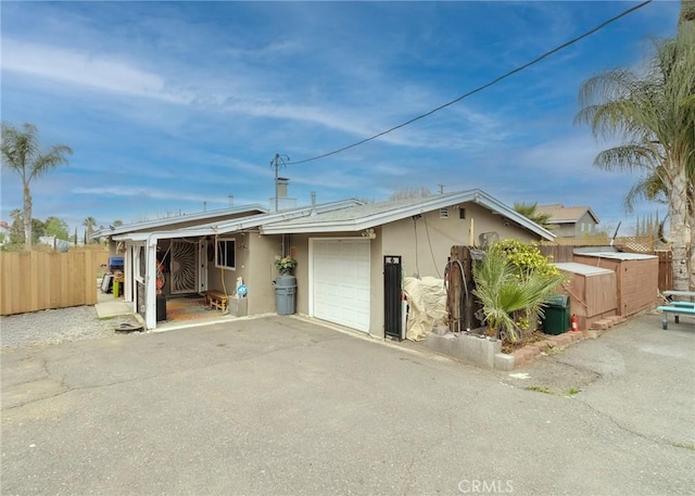 view of front of property with fence, driveway, an attached garage, and stucco siding