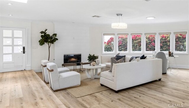 living room featuring ornamental molding, a fireplace, visible vents, and light wood-style floors