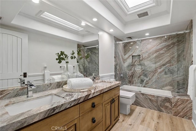 full bath with a tray ceiling, a sink, and visible vents