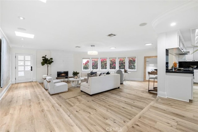 living room featuring light wood-type flooring, plenty of natural light, and visible vents