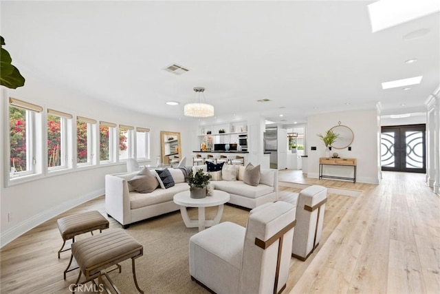 living room with a skylight, visible vents, baseboards, french doors, and light wood finished floors