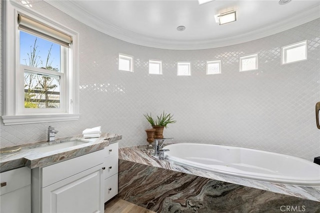 full bath featuring a bath, tile walls, crown molding, and vanity