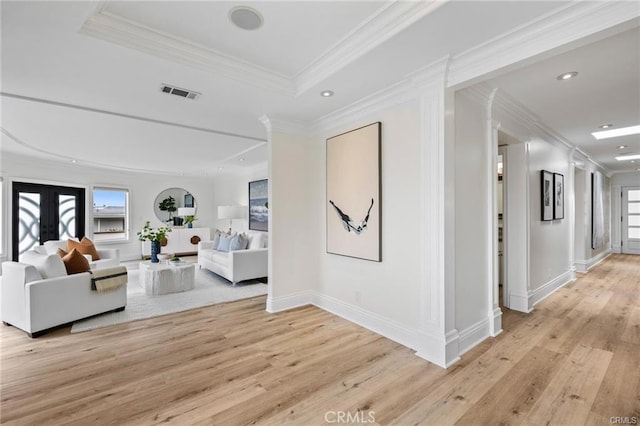 hallway featuring a tray ceiling, crown molding, light wood finished floors, recessed lighting, and visible vents