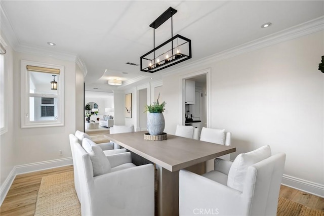 dining room with ornamental molding, visible vents, light wood-style floors, and baseboards