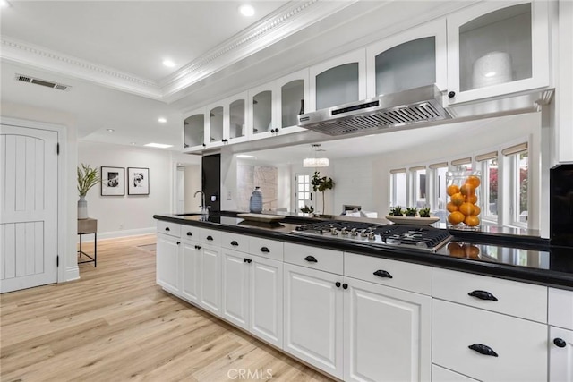 kitchen with visible vents, a raised ceiling, dark countertops, ornamental molding, and stainless steel gas cooktop