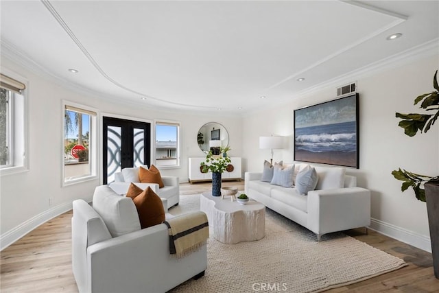 living area with french doors, light wood-style flooring, visible vents, and crown molding