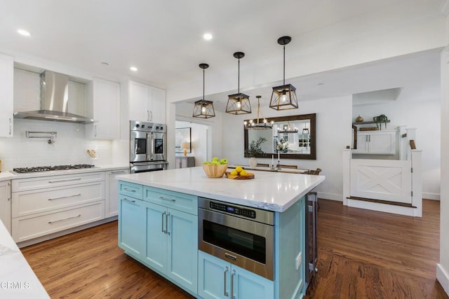 kitchen with wall chimney exhaust hood, stainless steel double oven, gas cooktop, and white cabinetry