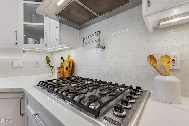 kitchen with glass insert cabinets, white cabinets, stainless steel gas stovetop, and tasteful backsplash