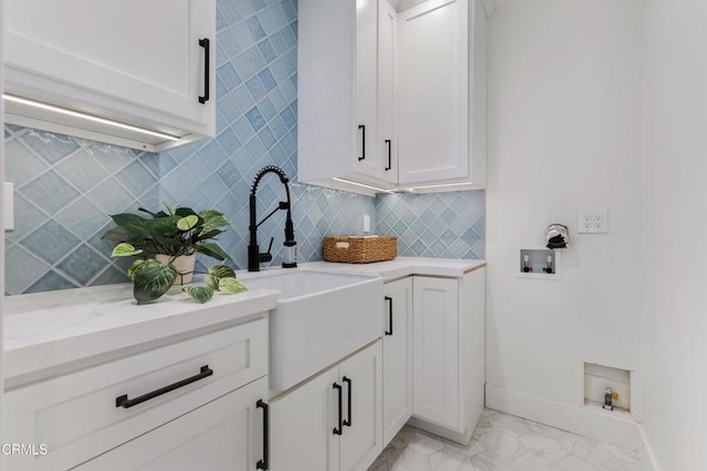 washroom featuring marble finish floor, hookup for a washing machine, cabinet space, a sink, and baseboards