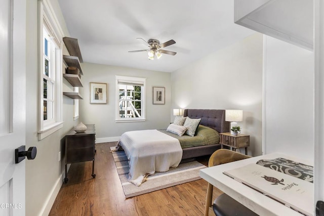 bedroom featuring a ceiling fan, baseboards, and wood finished floors