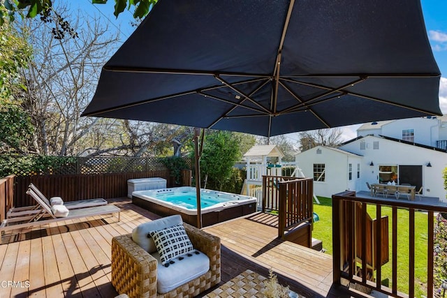 wooden terrace featuring hot tub deck surround, a lawn, and fence