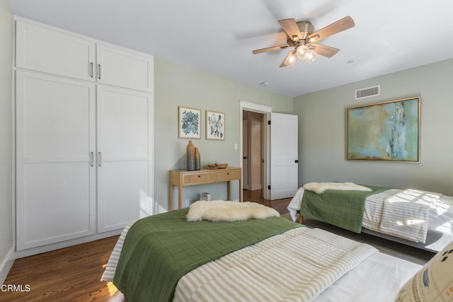 bedroom with dark wood-style floors, a closet, visible vents, and ceiling fan