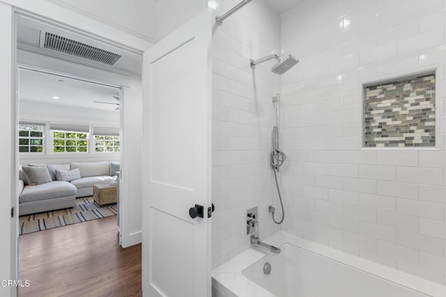 ensuite bathroom with tiled shower / bath combo, visible vents, wood finished floors, and ensuite bathroom