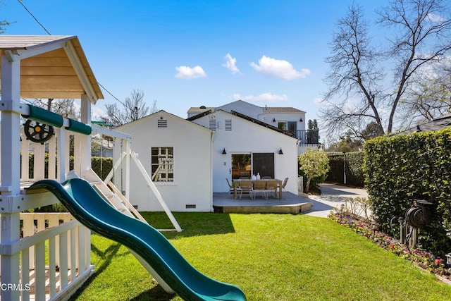 rear view of house with a playground, a yard, crawl space, stucco siding, and a patio area