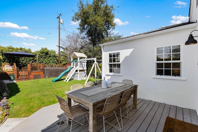 deck featuring a yard, outdoor dining area, and a playground