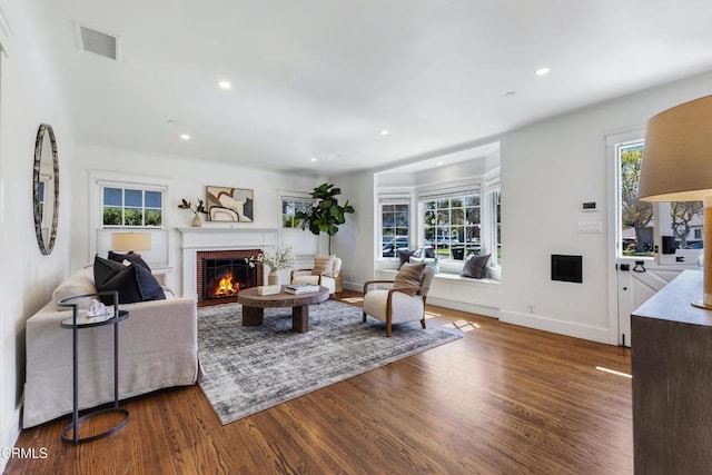 living room with recessed lighting, visible vents, a brick fireplace, wood finished floors, and baseboards