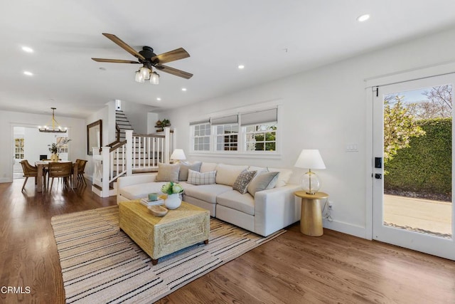 living room featuring ceiling fan with notable chandelier, stairway, wood finished floors, and recessed lighting