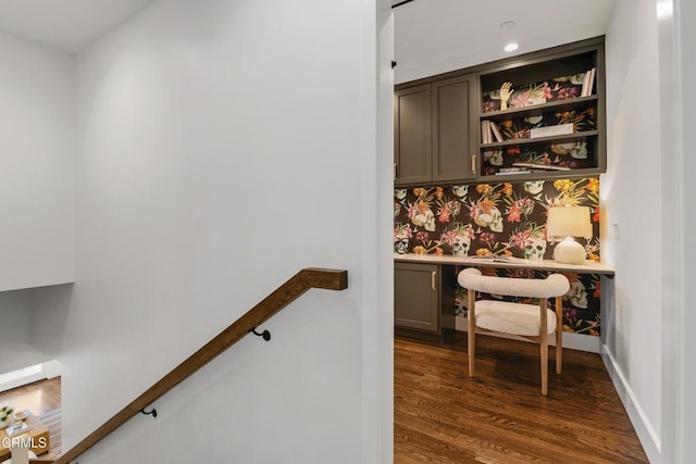 home office with wallpapered walls, built in desk, dark wood-style flooring, and baseboards