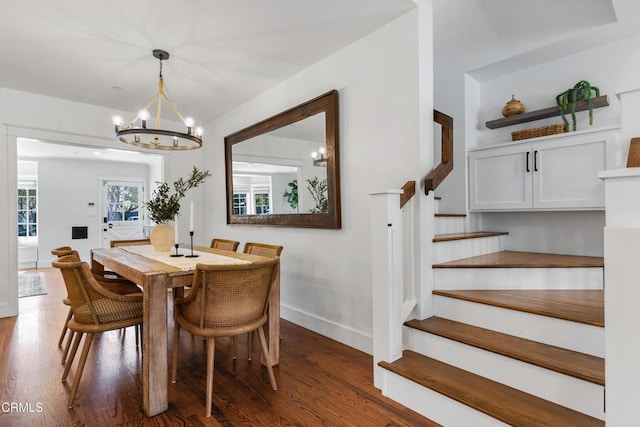 dining area with baseboards, a notable chandelier, stairway, and wood finished floors