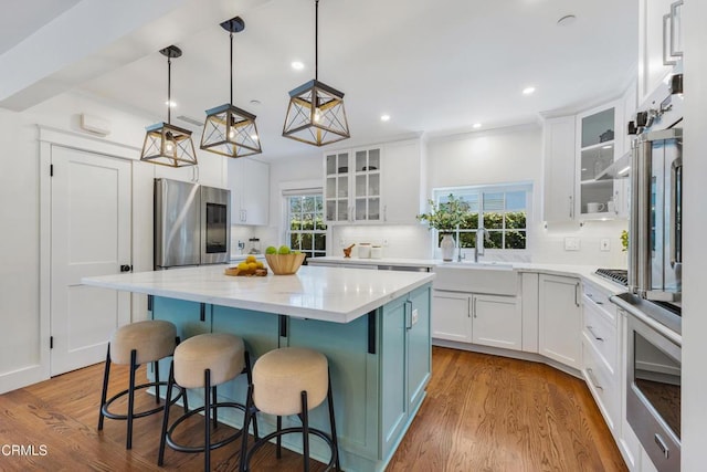 kitchen with stainless steel appliances, white cabinets, a sink, and a kitchen island