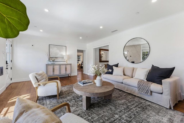 living area featuring baseboards, visible vents, wood finished floors, and recessed lighting