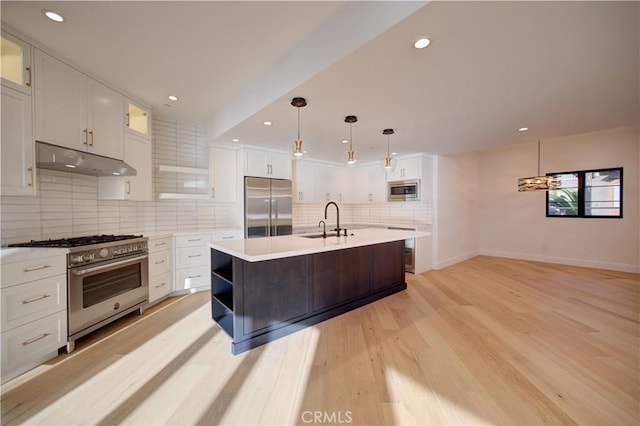 kitchen with white cabinets, built in appliances, light countertops, under cabinet range hood, and a sink