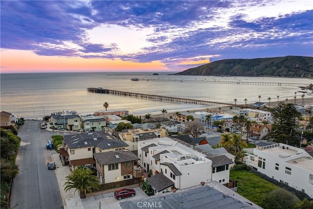 aerial view at dusk featuring a residential view and a water view