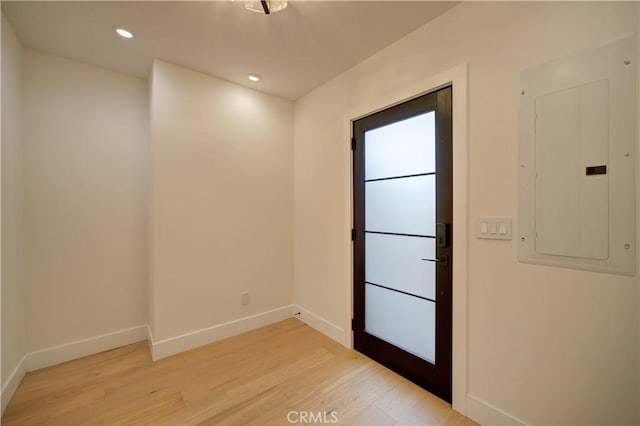 empty room featuring recessed lighting, electric panel, light wood-style flooring, and baseboards