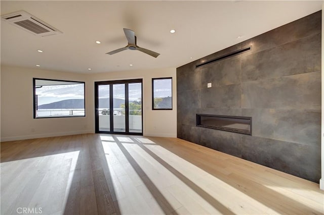 unfurnished living room with a tile fireplace, recessed lighting, wood finished floors, visible vents, and baseboards