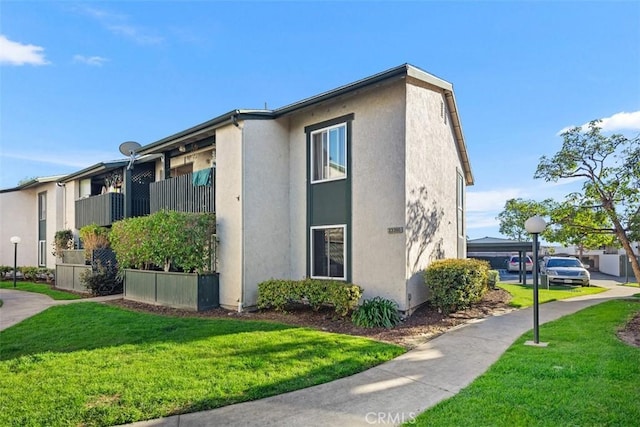 view of side of property featuring a lawn and stucco siding